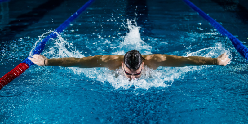 Man swimming in a pool doing a butterfly stroke.