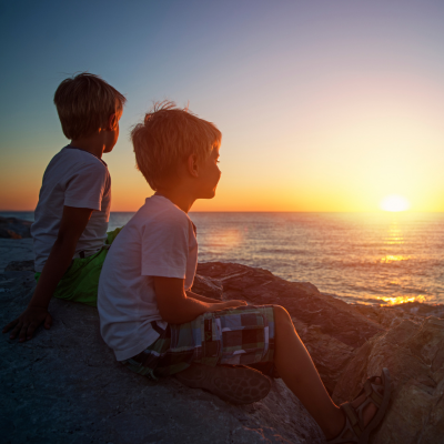 Two kids looking at a sunset over the ocean