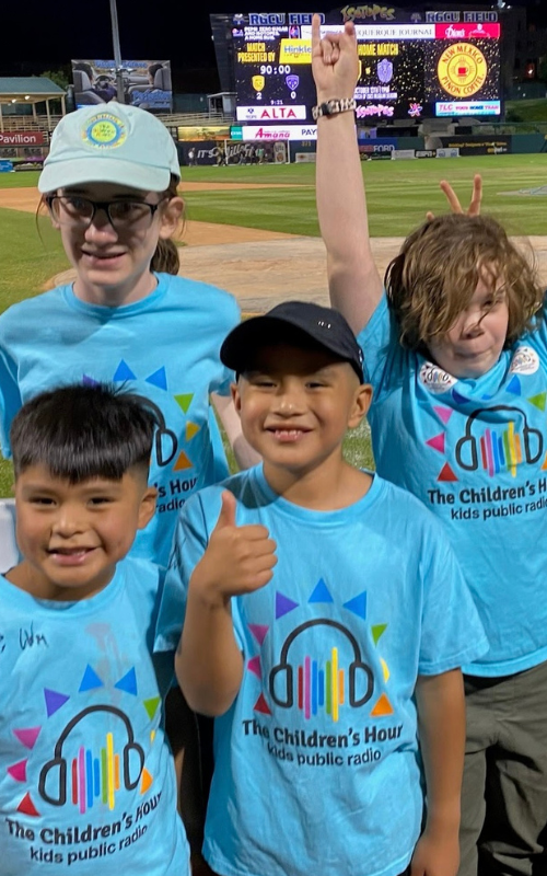 Four kids cheering, all wearing Children's Hour t-shirts