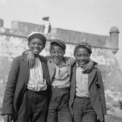 Three black teenagers smiling and standing arm in arm, taken in the 1930's or 1940's in Texas.