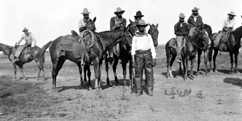 Black cowboys on horseback, and standing in front of horses, in Bonham Texas in 1913