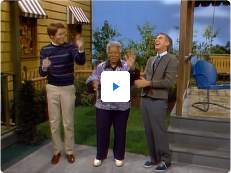 A still photo capture of the video of Ella Jenkins and her friend Chuck, laughing outside with Mr. Rogers.