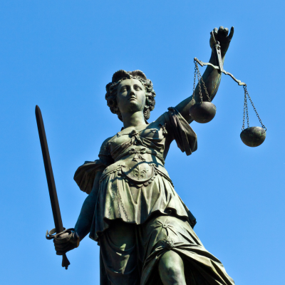 Statue of Lady Justice holding a scale and a sward, and with her eyes closed. Justice if fierce, equal, and blind.