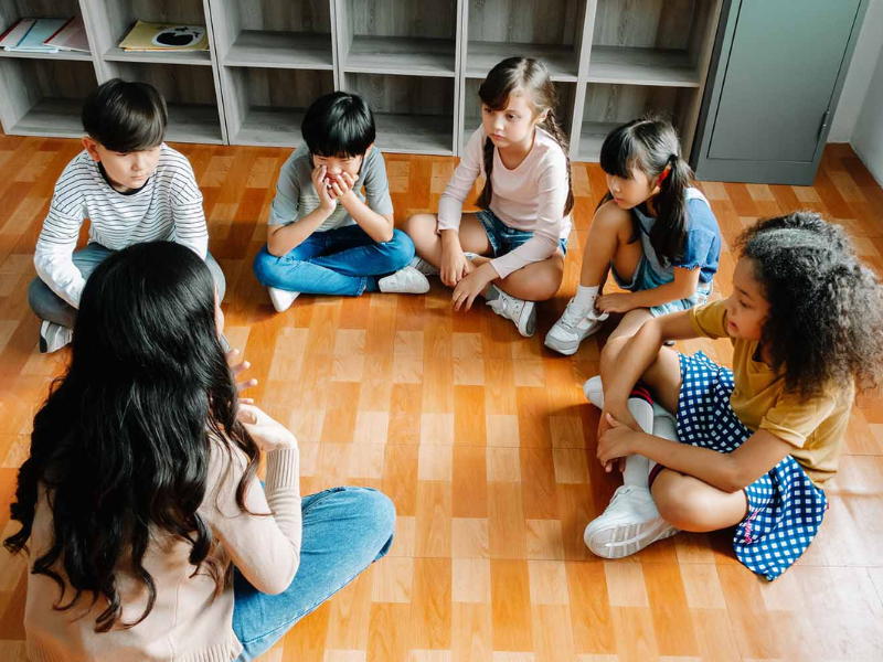 Kids sitting in a circle with an adult, practicing Restorative Justice